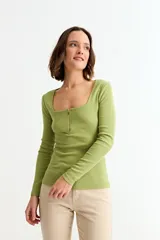 Remera de manga larga color verde lima, ajustada al cuerpo, con tejido acanalado y escote cuadrado con cierre metálico frontal.
