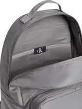 Mochila Calvin Klein color gris, confeccionada en poliéster reciclado. Cuenta con asa superior, correas de hombros acolchadas, compartimento principal con cremallera, bolsillo exterior en la parte delantera, funda para portátil y parte trasera de malla acolchada.