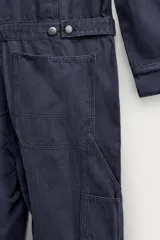 Mono oversize fit de algodón con estructura espiga en color azul marino, con cuello solapa en contraste de color tostado, manga larga, bolsillos de plastrón en el pecho con firma bordada, trabillas laterales en la cintura y cierre frontal con cremallera y botonadura oculta.