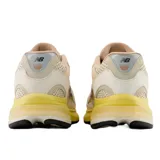 Championes urbanos New Balance modelo 2010, con diseño en tonos beige, crema y amarillo. Presenta una combinación de malla y gamuza en el exterior, con el logo N característico en el lateral y una suela de goma con entresuela amarilla destacada.