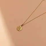 Conjunto compuesto por una cadena fina de eslabones y un dije circular con la imagen de San Benito, ambos realizados en oro 18k.