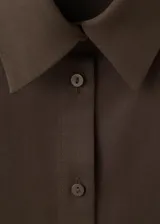 Camisa de lyocell color marrón oscuro, de manga larga y diseño fluido con cuello camisero y cierre frontal abotonado.