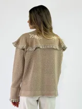 Saco tejido de punto color azul con diseño calado, cuello grande con bordados florales en tono crudo, volados decorativos y cierre frontal con un botón.