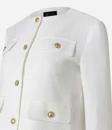 Chaqueta de manga larga confeccionada en tejido tweed color negro, con cuello redondo, cierre frontal mediante botones metalizados dorados y bolsillos frontales con solapa y botones a juego.