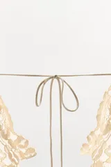 Vestido midi de color beige con escote en pico y tirantes anchos. Presenta un diseño con tejido plisado en la parte superior y aplicaciones de encaje a tono en el escote y la cintura. Cuenta con una tira ajustable con lazada en la espalda y forro interior.