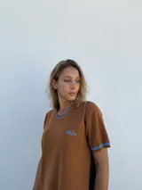 Vestido corto marrón tejido en hilo, con mangas cortas y cuello redondo.