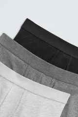 Pack de tres calzoncillos tipo bóxer en gris claro, gris oscuro y negro, con cintura elástica.