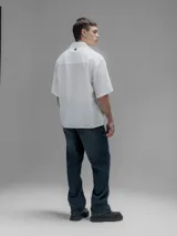 Camisa blanca de manga corta, con cuello clásico y cierre de botones frontal.