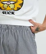 Pijama masculino de algodón, compuesto por una remera blanca con estampado de Garfield y la frase "Mondays Suck", y un short con rayas verticales blancas y negras. Incluye pantuflas negras de felpa.