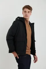 Campera impermeable negra con capucha, cierres a tono y cursores negros metalizados, bolsillos frontales con tapa, elásticos regulables en el ruedo e interior térmico con detalles confeccionados con láser.