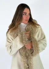 Chaqueta midi color crudo con detalles de piel sintética en el cuello y los puños. Presenta un diseño abierto con bolsillos laterales y una textura suave.