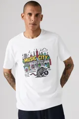 Remera blanca Levi's de corte relajado, con cuello redondo, mangas cortas y estampa frontal colorida con la leyenda 'Music City' y diseño de ciudad con un animal sosteniendo un disco de vinilo.