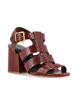 Sandalias de tacón alto ancho de líneas arquitectónicas, con diseño de tiras múltiples estilo cangrejera y cierre de hebilla metálica en el tobillo. Confeccionadas en cuero con estampado texturizado tipo cocodrilo color marrón chocolate.