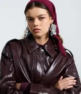 Campera bomber de poliuretano color marrón oscuro, con cuello clásico, cierre frontal con botones a presión, bolsillos delanteros con solapa, puños y bajo elásticos, y recortes estructurados.