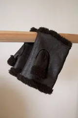 Mitones marrones de cuero con interior de corderito. Diseño sin dedos y puño con borde de corderito. Talle único.