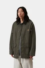 Campera de gabardina Carhartt WIP modelo Prescott, color verde militar, con cuello camisero de pana negra contrastante, cierre frontal de botones y bolsillos frontales amplios. Cuenta con detalle de logo bordado en el pecho.
