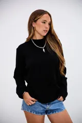 Sweater de punto acanalado en color negro, con cuello redondo y mangas largas. Presenta un diseño de corte recto y textura acanalada vertical.