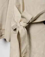 Campera trench de gabardina en color beige, con solapa cruzada, doble botonadura frontal, hombreras y cinturón ajustable para anudar en la cintura. Presenta bolsillos delanteros y puños ajustables con tiras.