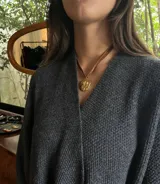 Collar con cinta de terciopelo marrón y dije circular de metal dorado con relieve de San José y el Niño Jesús. El dije cuenta con acabado chapado en oro 18k.