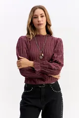 Blusa de algodón en color bordó con textura fruncida, cuello alto con volado, mangas largas con puños elásticos y terminación en volado.