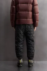 Pantalón de esquí acolchado con diseño de rombos, color negro. Presenta cintura elástica con cierre de botón a presión, bolsillos laterales con cremallera y bajos ajustables con cordón elástico.