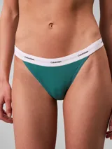 Conjunto de ropa interior de dos piezas compuesto por un corpiño triangular y una bombacha tipo tanga, ambos confeccionados en algodón con textura acanalada en color verde azulado. El corpiño cuenta con tirantes finos ajustables y una banda elástica inferior con el logo de la marca, mientras que la bombacha presenta un corte de talle medio con la misma banda elástica distintiva.