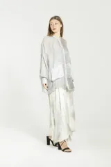 Camisa de viscosa y seda gris, de corte boxy y diseño semitransparente. Posee cuello mao, cierre frontal con botones, mangas largas con puños, bolsillos grandes en el frente y detalles de satén.