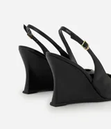Zapato tipo slingback de color negro con acabado liso. Presenta punta fina, tira trasera ajustable con hebilla metálica y un diseño de taco anabela integrado a la suela.