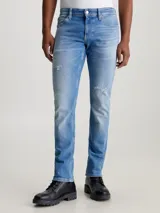 Pantalón de jean celeste con roturas en las rodillas, corte slim, tiro bajo y cinco bolsillos.