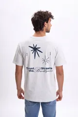 Remera de manga corta color gris melange con efecto lavado. Presenta una estampa gráfica en la espalda con estrellas y la frase 'Trust the Brooklyn Streets'.