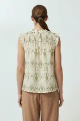 Blusa sin mangas color crema con estampado abstracto en verde oliva y cuello con punto smock.