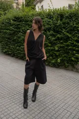 Blusa negra sin mangas con escote en V cruzado y drapeado en la parte delantera.