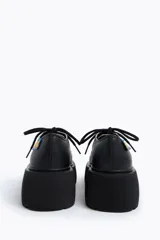 Zapato blucher acordonado de piel color blanco con ojetes metálicos y etiqueta textil personalizada en el lateral. Plataforma de goma logotipada color negro.