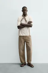 Jeans de hombre, tiro medio, color marrón claro o caqui, con corte relaxed fit y perneras anchas. Presenta cinco bolsillos y costuras laterales giradas hacia el frente.