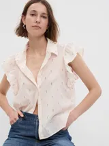 Camisa de color crema con estampado de pequeños puntos multicolores, cuello clásico, cierre frontal con botones y mangas con volados.