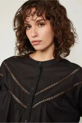 Camisa negra de manga larga estilo globo, justa al cuerpo con detalles de aberturas pequeñas que generan una trama en el pecho y en las mangas.