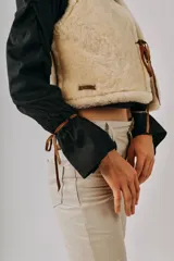 Chaleco de cuero marrón con interior y detalles de corderito sintético blanco, diseño sin mangas con cordones laterales ajustables.