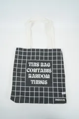 Bolso tote de tela con estampado de rayas verticales rosadas y blancas, laterales y asas en color beige. Presenta la palabra "BONJOUR" en verde en el centro y "INDIAN" en la parte inferior.