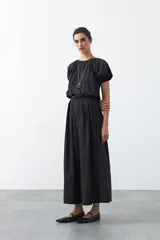 Falda larga plisada color marrón, de silueta amplia y caída fluida.