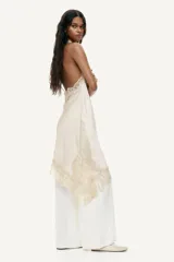 Vestido corto de satén color beige, con escote drapeado, diseño halter y bajo asimétrico con detalles de encaje.