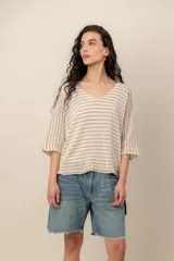 Sweater de tejido de punto a rayas horizontales en tonos beige y blanco, con escote en V y mangas cortas holgadas.