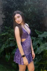 Vestido corto negro con estampado de plumas doradas, escote en V, breteles finos cruzados en la espalda, cut-outs laterales y volado en el ruedo.