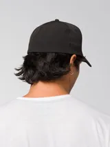 Gorro tipo cap de color negro con visera curva y logo de la marca CAT impreso en relieve en la parte frontal.