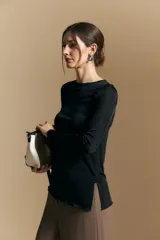 Top de manga larga con textura suave y leve brillo. Presenta una silueta al cuerpo, tajos laterales y terminaciones onduladas en el ruedo.