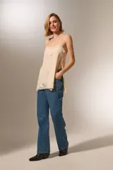 Musculosa de poliamida color negro, con breteles finos, escote profundo y detalles de encaje en el escote y el ruedo. Presenta un diseño holgado.