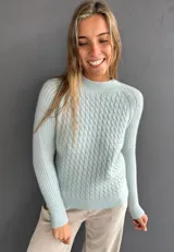 Sweater de punto con textura suave, color celeste, con diseño de ochos en el frente y tejido morley en mangas y espalda. Presenta cuello redondo a la base y mangas largas.