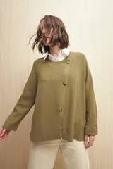 Sweater color beige de tejido de punto con cruce irregular y botones a contraste.