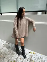 Sweater tejido color beige con cuello alto y mangas largas.