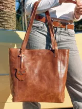Bolso shopper de cuero color marrón con asas al hombro y dije colgante en forma de búho.
