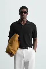 Polo negro de manga corta con cuello solapa y abertura frontal. Presenta un tejido jacquard con textura geométrica sutil.
